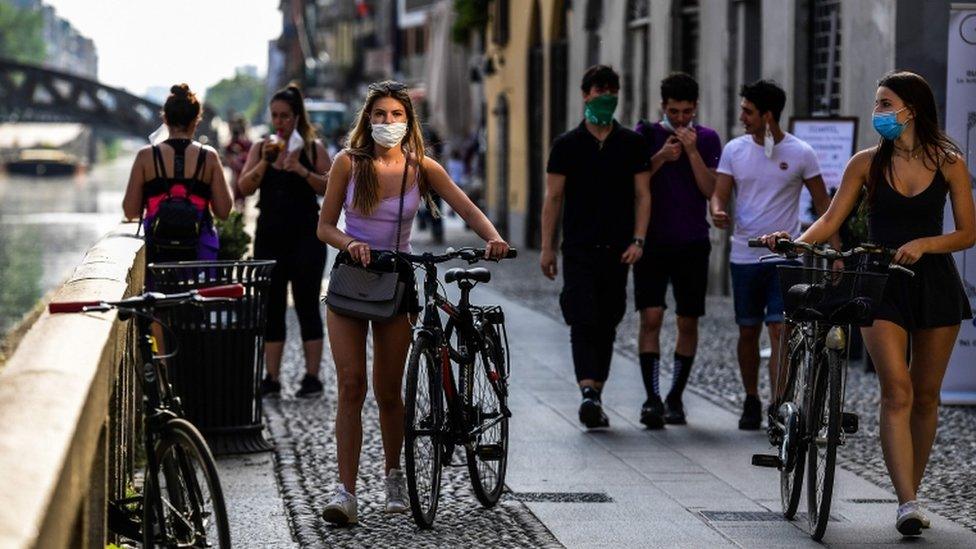 People stroll along the Navigli canals in Milan on May 8, 2020