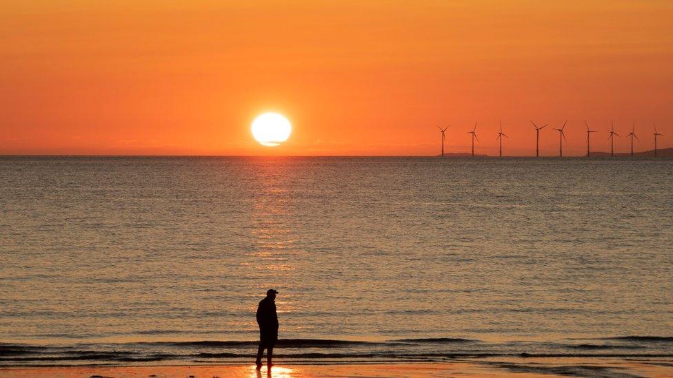 Sunset over the sea with man silhouetted on the beach