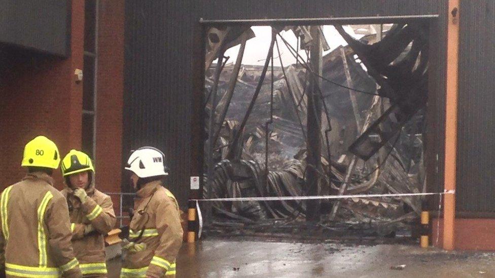 Three firemen outside a burnt warehouse