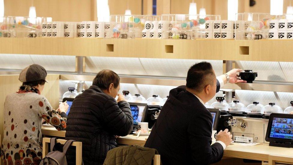 Customers seated at a sushi conveyor belt restaurant in Tokyo