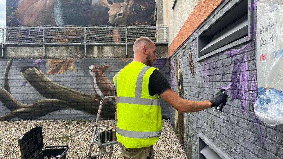 Jordan Lauder painting a brick wall