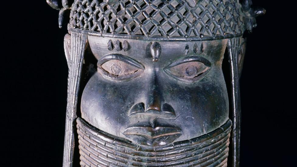 A head of an oba from an ancestral shrine. The head has a high coral collar and a beaded cap with coral clusters in British Museum collection