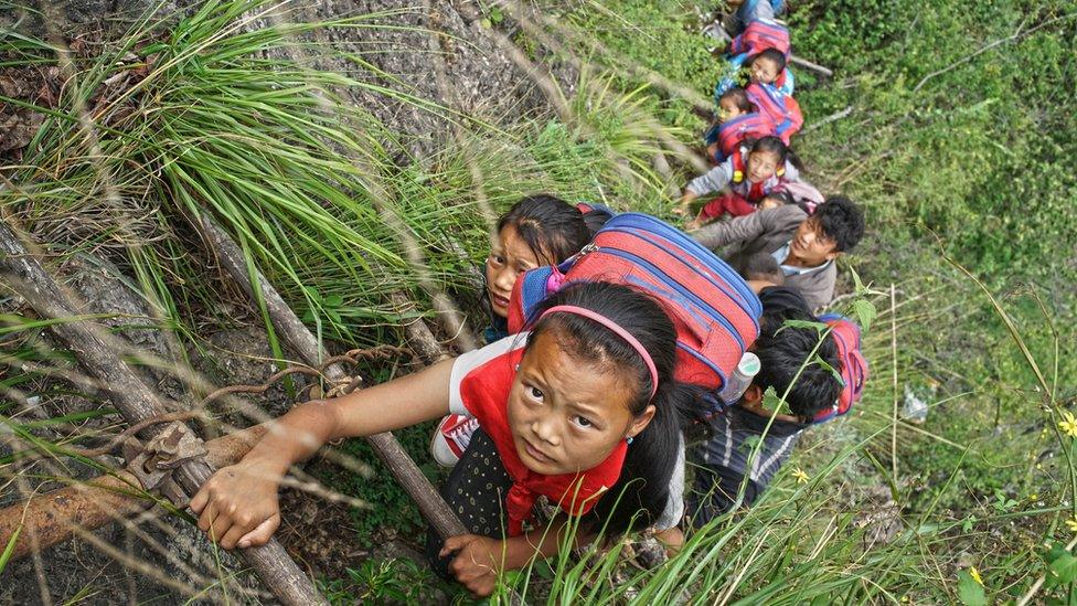 Children of Atuler Village climb the vine ladder on a cliff on their way home in Zhaojue county in southwest China's Sichuan province on May 14, 2016 in Zhaojue, China