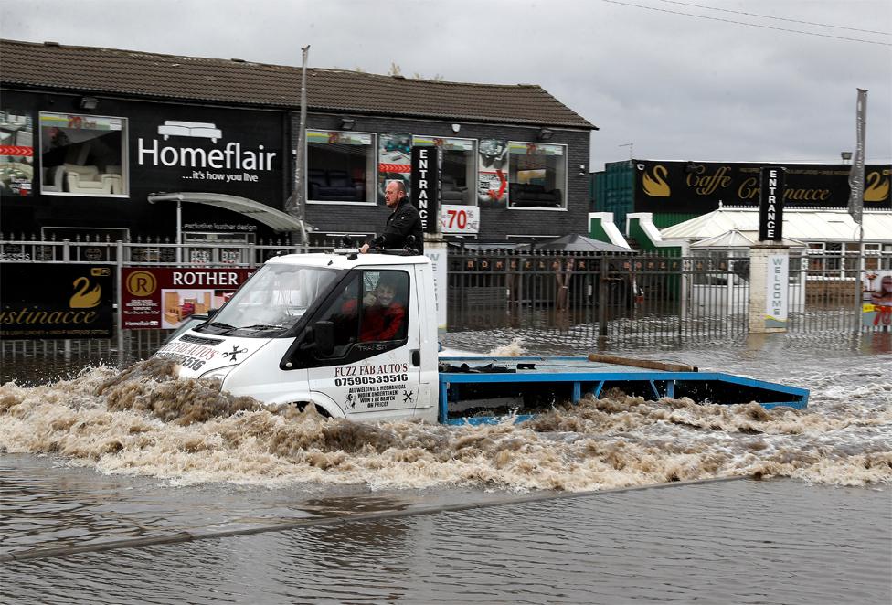 A man drives a truck through flood waters