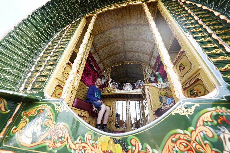 A young traveller sits in a colourful caravan at Appleby