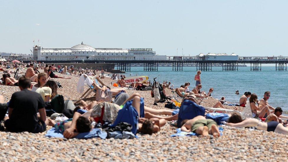 People relax in the sunshine on the beach in Brighton, Sussex