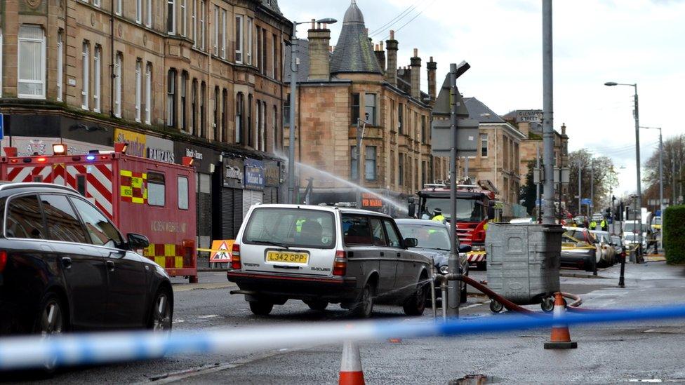 A view of the collapsed building with police tape in the foreground