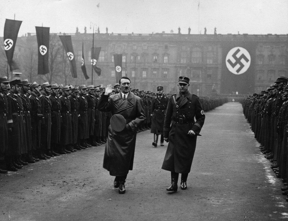 Adolf Hitler walks past two files of guardsman in front of a huge swastika at a parade at the Lustgarten, Berlin in 1936