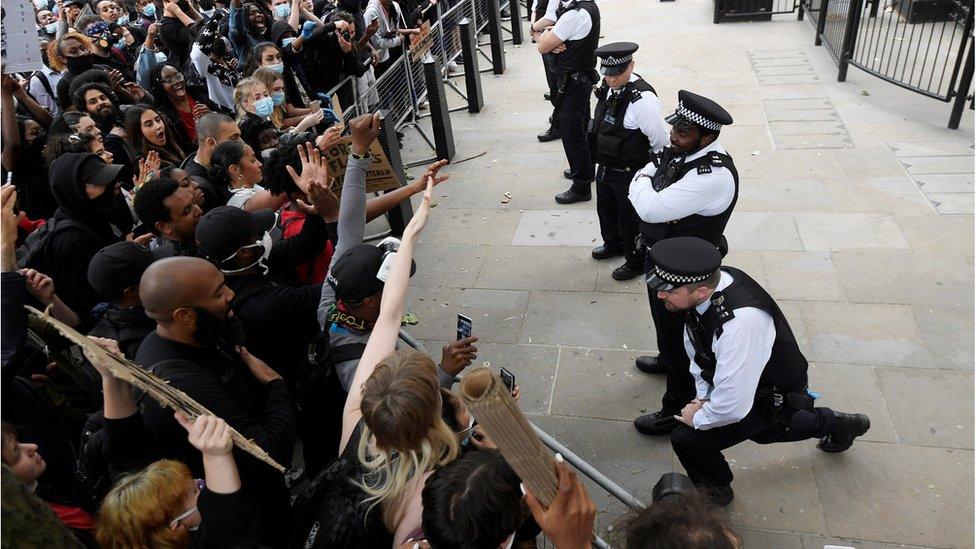 A white police office kneels outside Downing Street