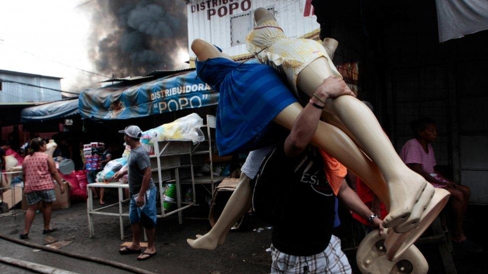 A man carries mannequins away from Mercado Oriental in Managua