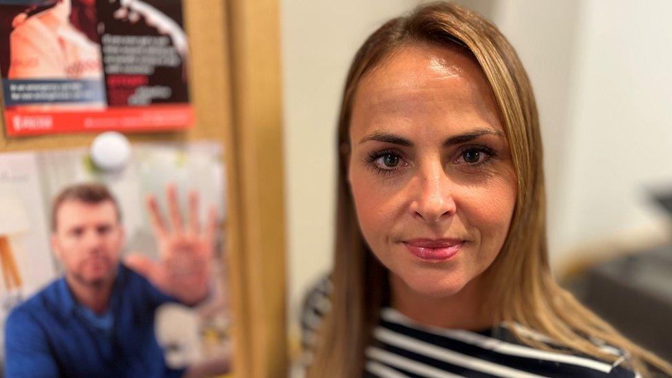 Sophie Williams inside her Nationwide branch stood in front of two anti fraud posters