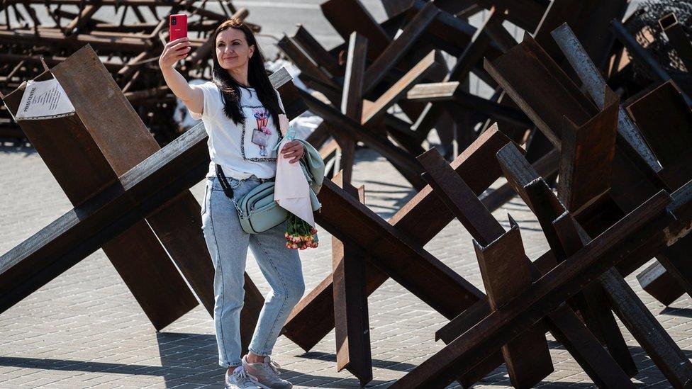 A woman takes a selfie by anti-tank barricades in Kyiv