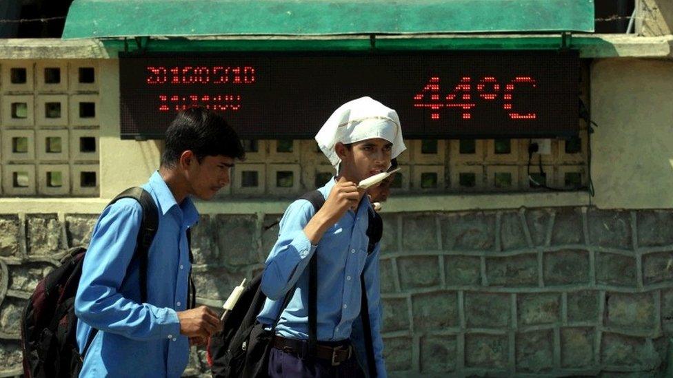 Indian school children eat ice cream as they walk near the LED display showing weather forecast on the outskirts of Jammu the winter capital of Kashmir, India, 18 May 2016.