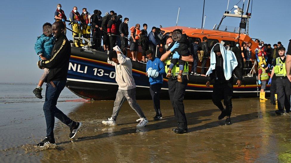 Migrants with children are escorted after being picked up by a lifeboat while crossing the English channel at a beach in Dungeness, southeast England.