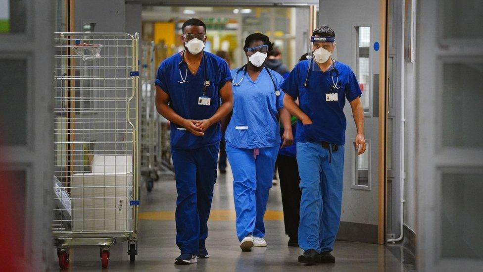 Hospital works walking in a corridor wearing scrubs and PPE