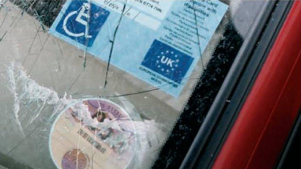 A smashed windscreen on a car with a disability badge