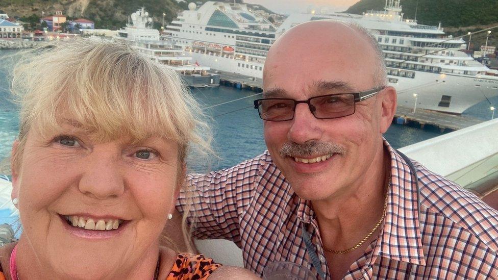 Lara Barnes and her husband pose in front of a cruise ship