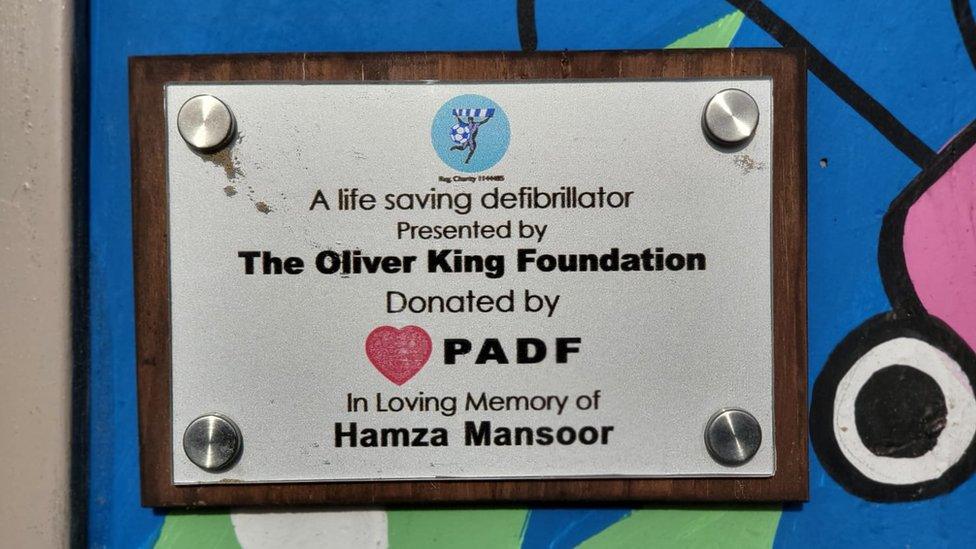 Plaque on the side of the United Utilities building crediting the charities donations and reading 'In loving memory of Hamza Mansoor'