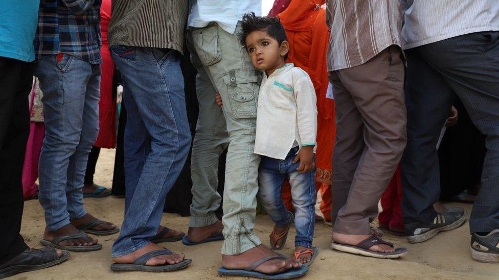 A little boy clutches his father outside a polling booth in Ghaziabad in Uttar Pradesh state