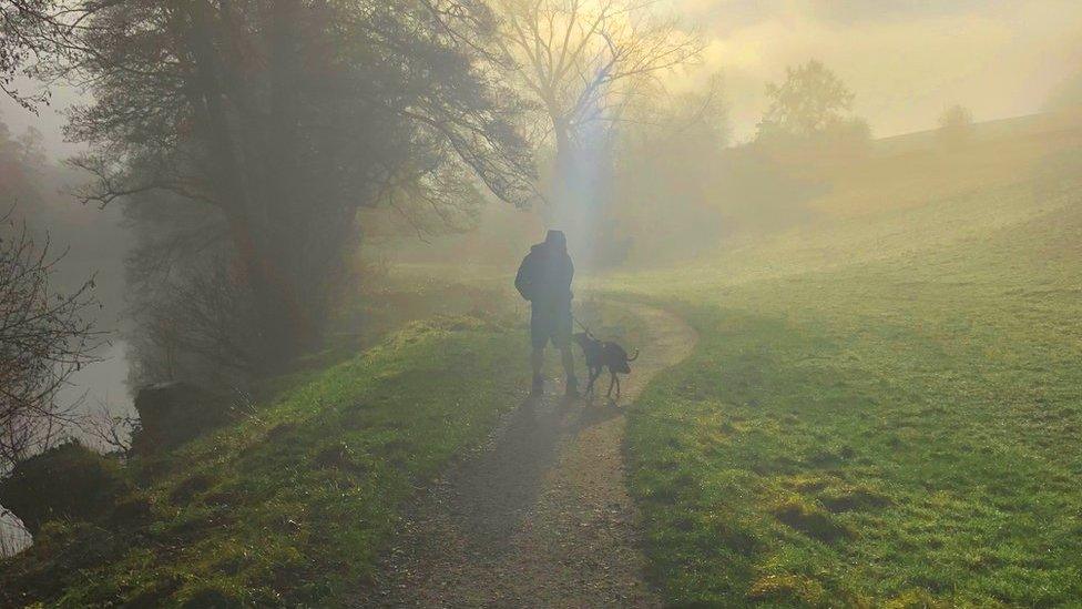 Mist around a dog walker in the village of Curbar in Derbyshire