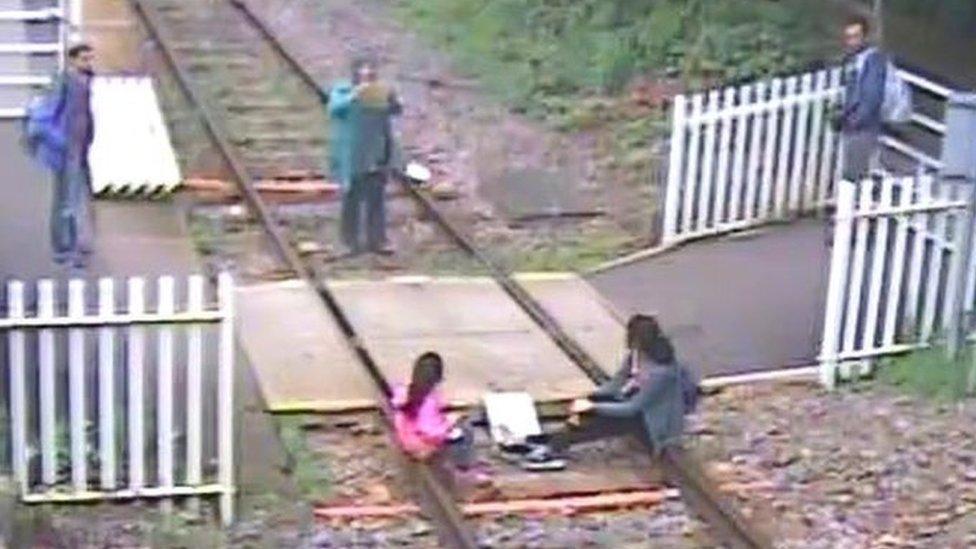 Children sit on rails while mother takes photos