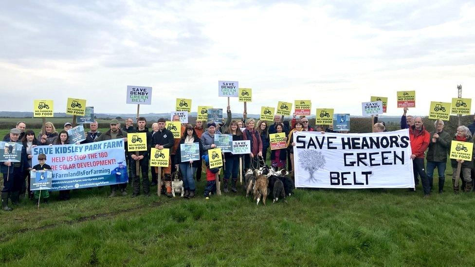 Protesters gather for photo with placards and banners