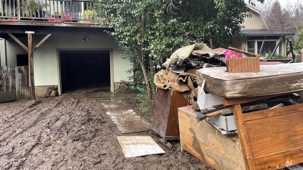 Ms Baxter's home is surrounded by a mess of water and mud