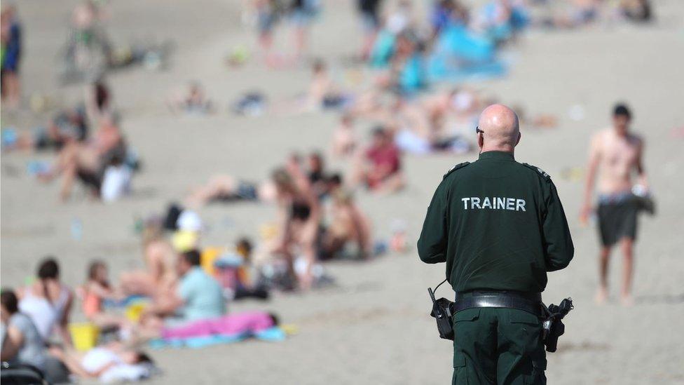 A PSNI officer views the crowd enjoying the sunshine at Ballyholme beach on Sunday 31 May