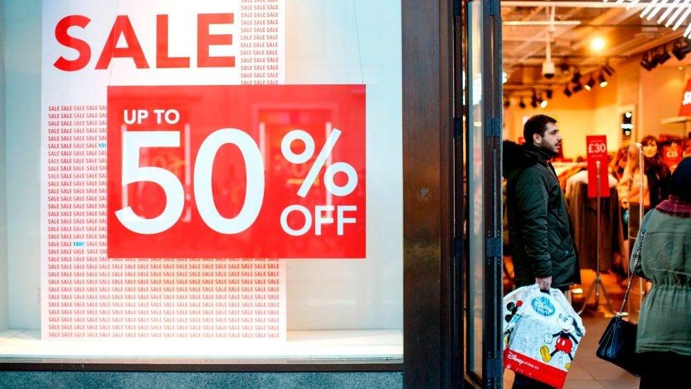 A shopper stands in the door of a shop advertising sale discounts on onOxford Street in London on December 13, 2018 less than two weeks before Christmas.