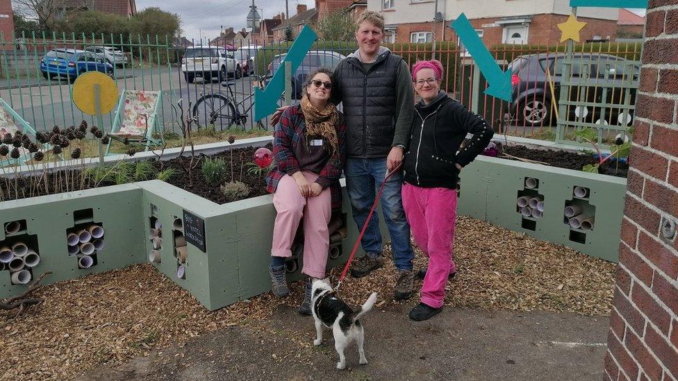 Three people stand next to new planters at Filwood Community Centre in Brustik