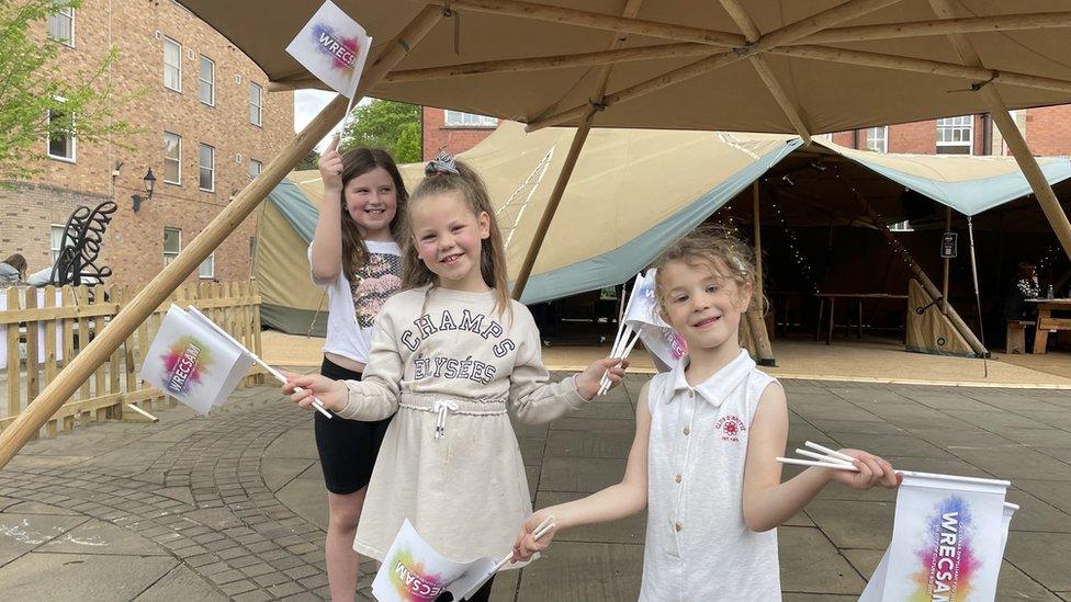 L-R: Jessie, Lily and Evie wave Wrexham 2025 bid flags