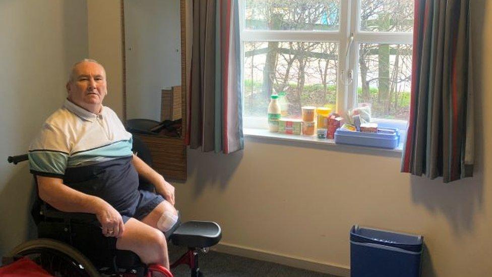 Peter Shanks in his wheelchair at the window of his Travelodge room