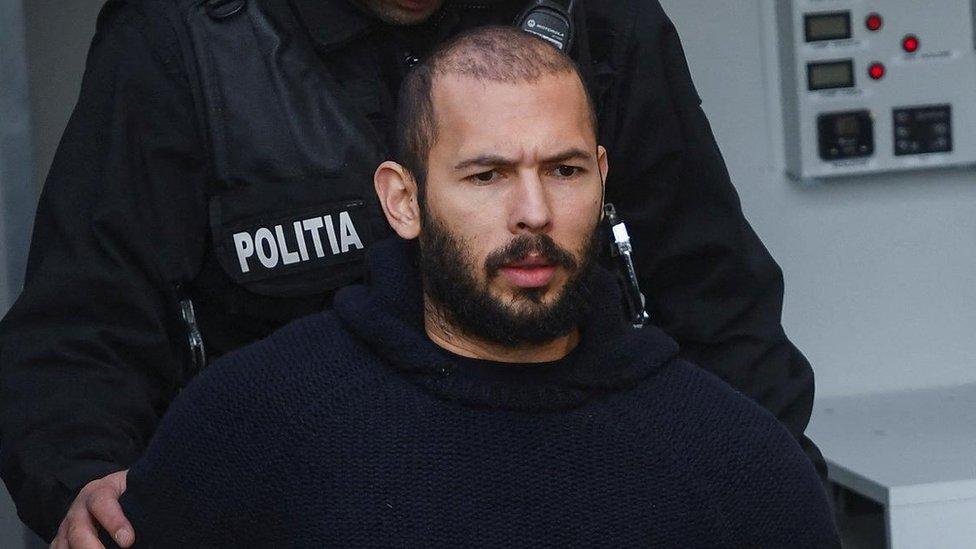 Andrew Tate escorted by police officers outside the headquarters of the Bucharest Court of Appeal, in Bucharest, Romania, February 1, 2023.