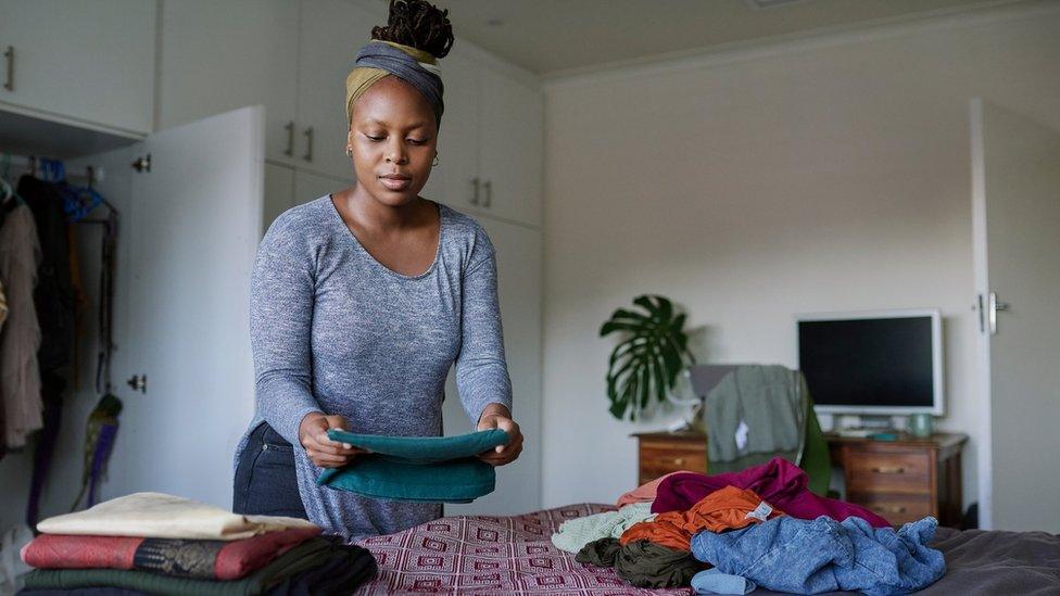 A woman folds laundry on a bed