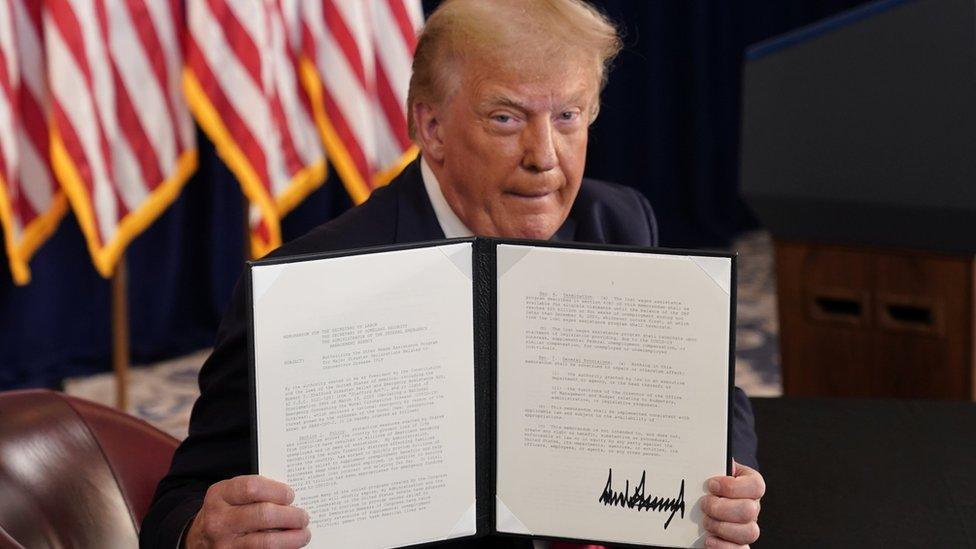 US President Donald Trump shows signed executive orders for economic relief