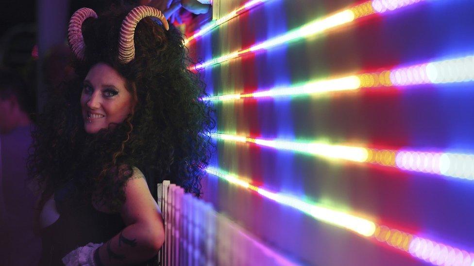 A woman wearing devil horns in front of a rainbow light prepares for the annual Gay and Lesbian Mardi Gras parade in Sydney, Saturday, March 4, 2017.