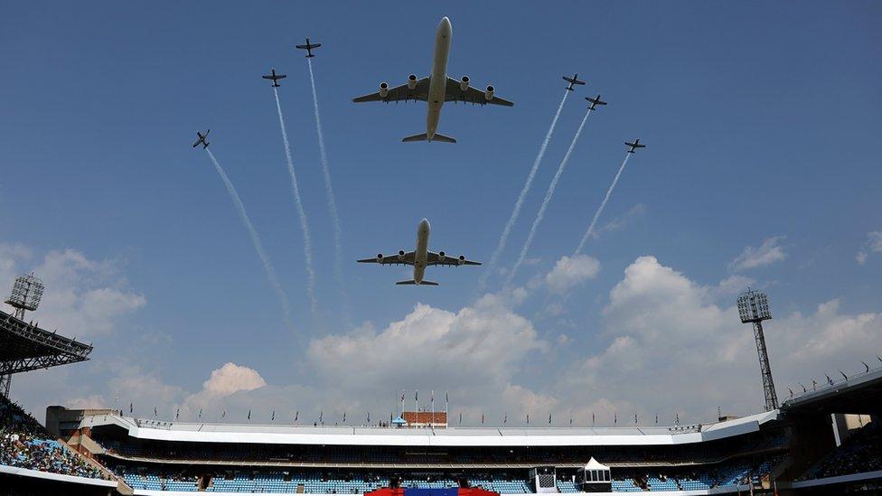 Two large planes and a fleet of small ones flying over the stadium