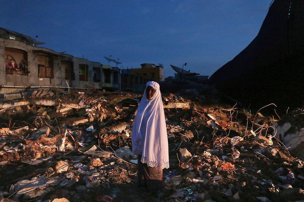 A woman stands on the ruin of a market after Wednesday's earthquake in Meureudu, Aceh province, Indonesia, early Thursday, 8 December 2016