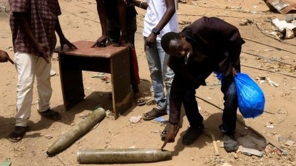 People look at shells on the ground in northern Khartoum