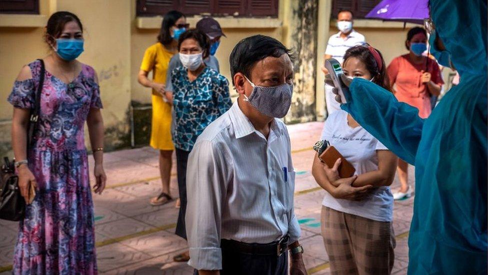 People who recently returned from Da Nang city wear face masks while queuing in safe distance to take the coronavirus disease rapid test on July 31, 2020 in Hanoi, Vietnam.