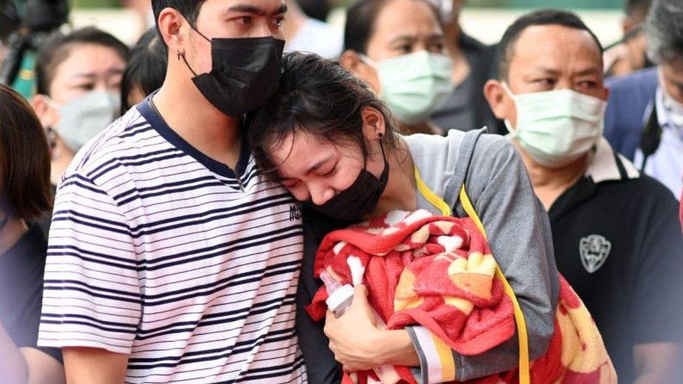 The mother of a victim holds a milk bottle and blanket as she reacts while standing outside the nursery in Na Klang in Thailand's northeastern Nong Bua Lam Phu province on October 7, 2022