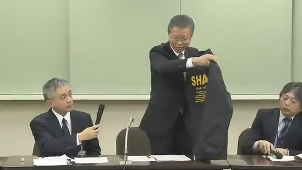 An official holding up one of the jackets