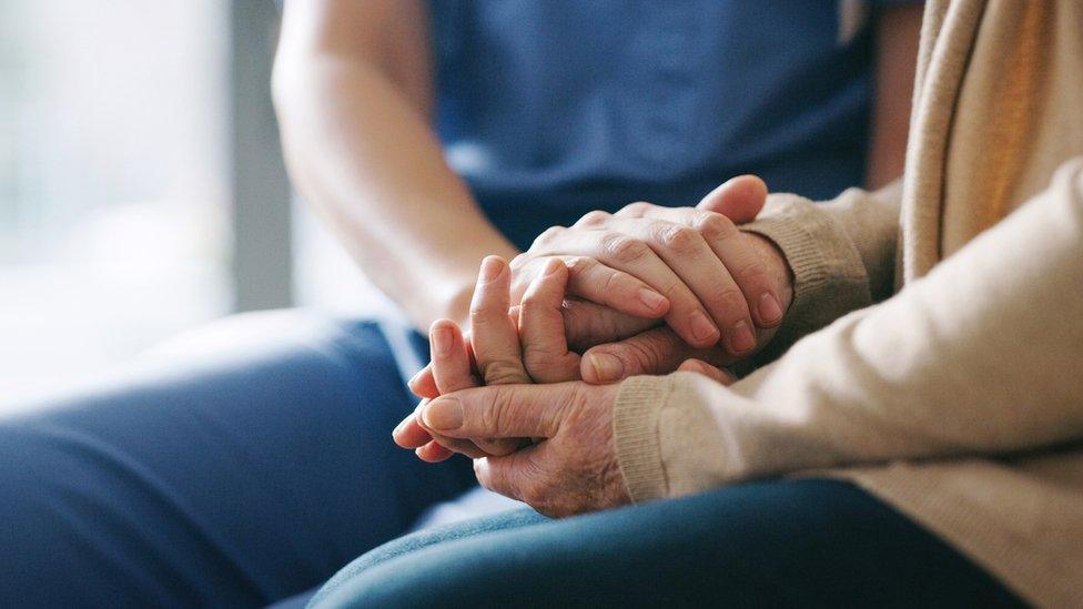 Cropped shot of a senior woman holding hands with a nurse