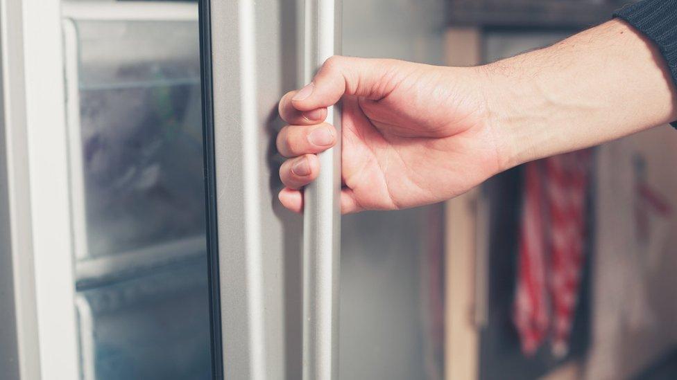 man opens fridge door