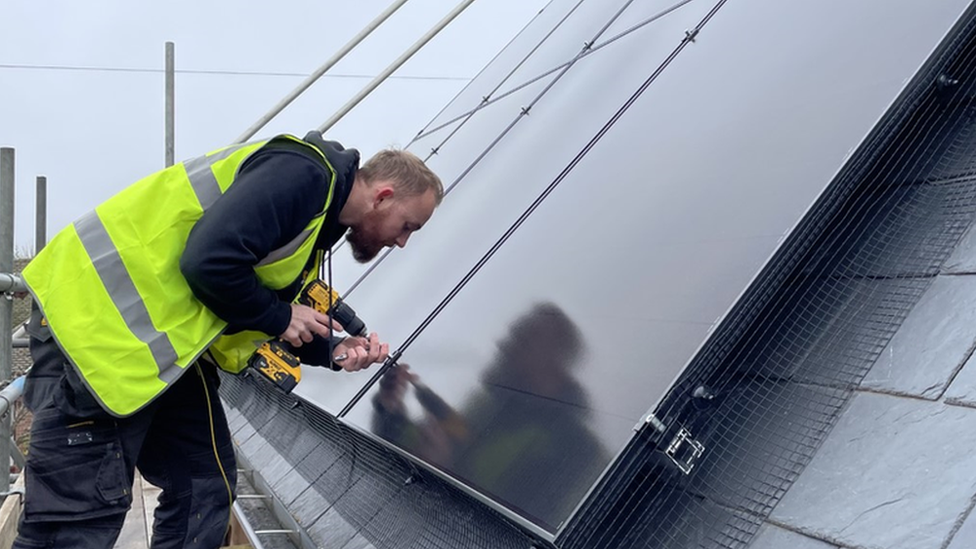 An installer working on an array of solar panels