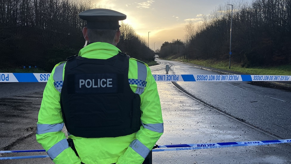 Police officer at cordon near scene of crash