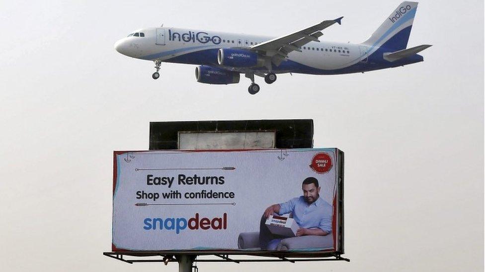 An IndiGo Airlines aircraft flies above an advertisement of Indian online marketplace Snapdeal featuring Bollywood actor Aamir Khan, in Mumbai, India, October 16, 2015.