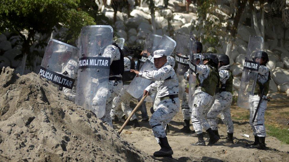 Members of Mexico's National Guard hold their shields to block migrants