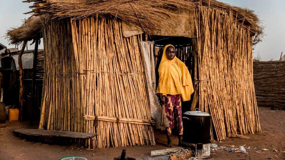 Woman standing in front of a thatched hut