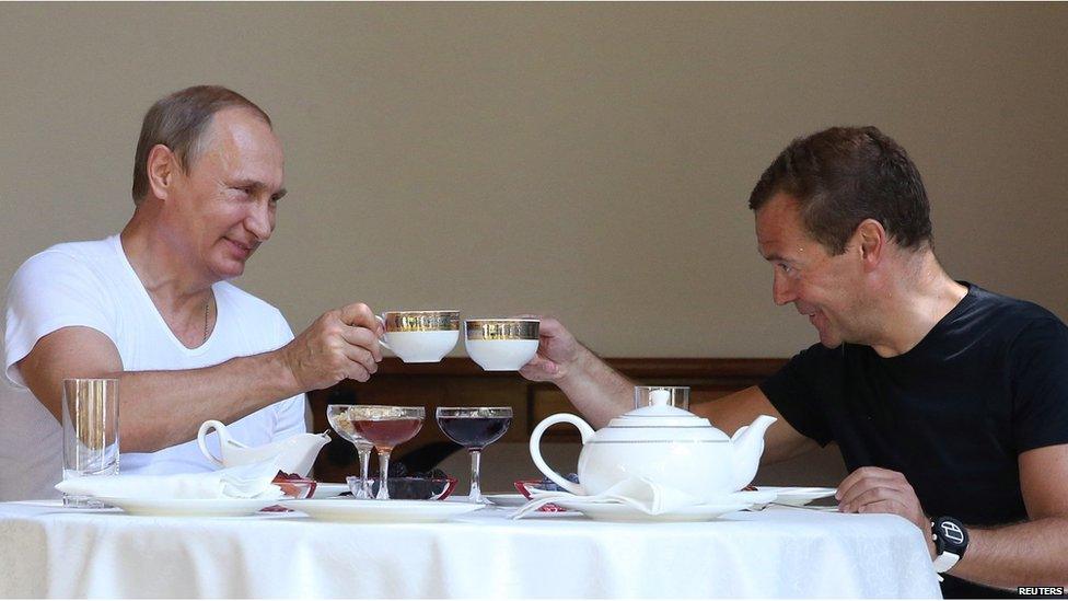 Russias President Vladimir Putin (L) and Russian Prime Minister Dmitry Medvedev raise their cups for a toast during a breakfast at the Bocharov Ruchei state residence in Sochi on August 30, 2015.